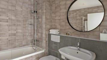 Une salle de bain moderne équipée d’une baignoire, de toilettes et d’un lavabo.