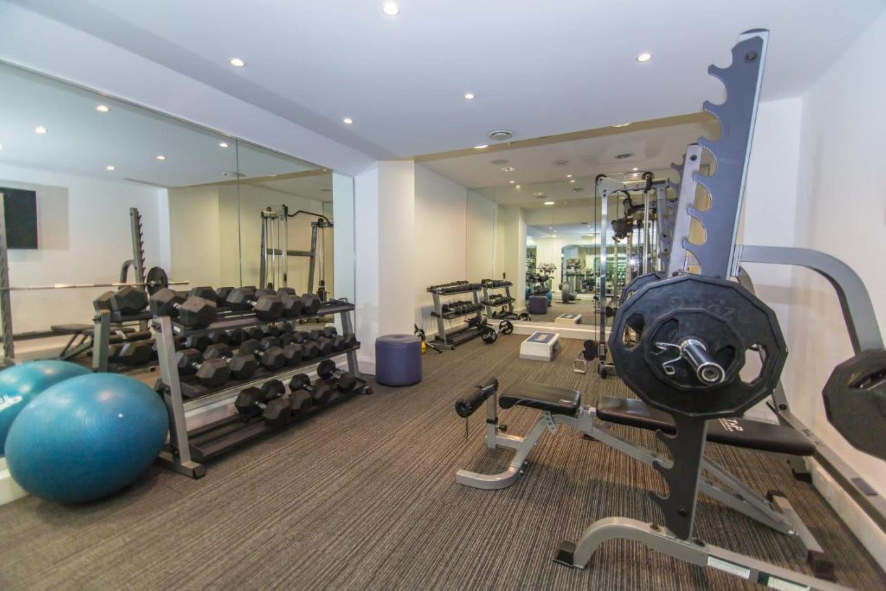 Ein Fitnessstudio mit Krafttrainingsgeräten, Gymbällen und Kurzhanteln.