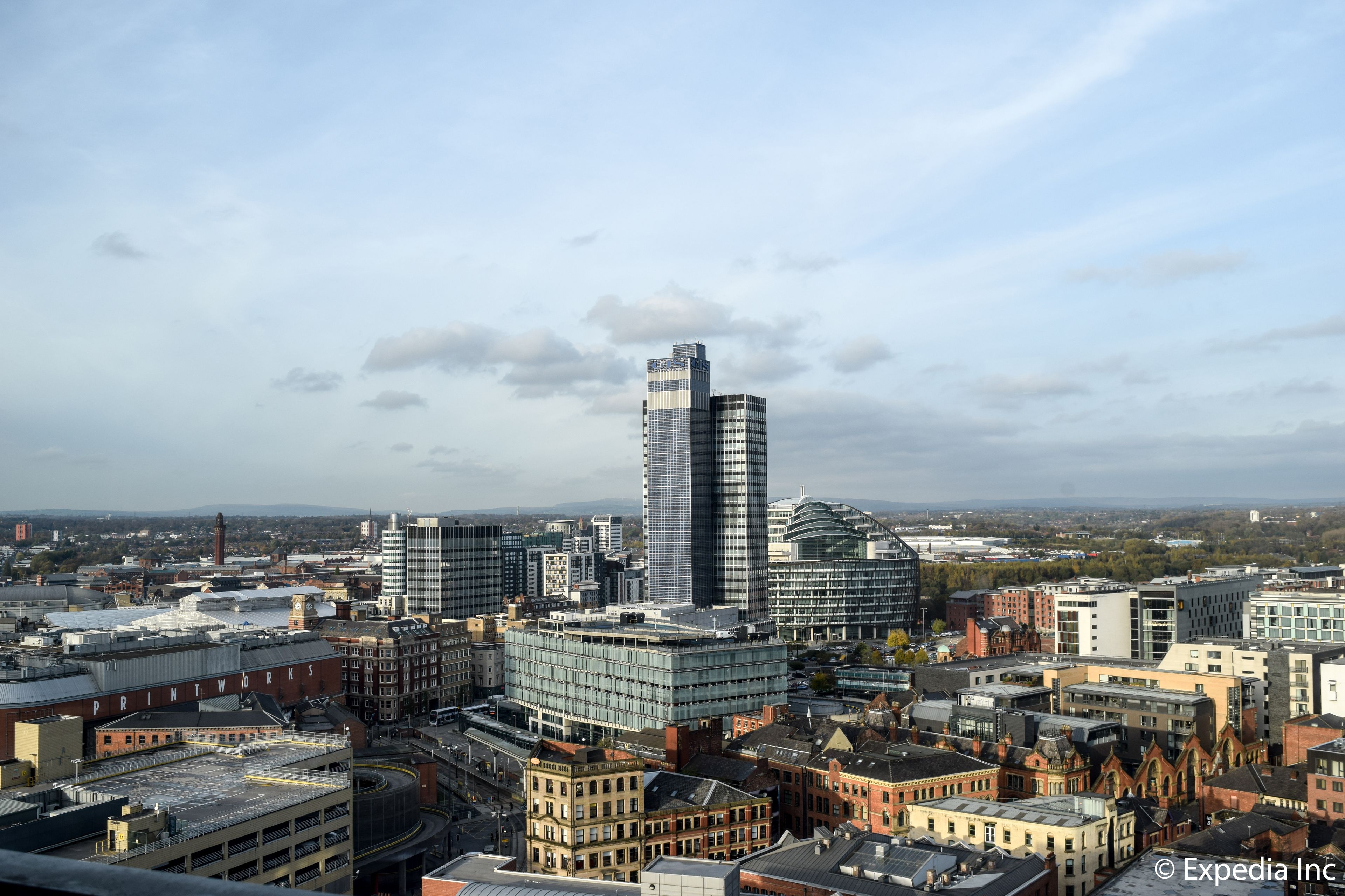A cityscape with a mix of modern and traditional buildings, including a prominent skyscraper and a historic building with a clock tower.