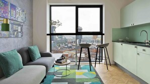 Un apartamento moderno con un amplio ventanal, un sofá, una cocina y vistas a la ciudad.