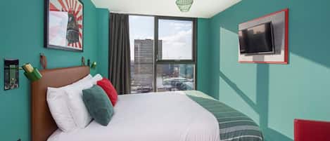 A modern hotel room with a large bed, a TV mounted on the wall, and a city view through the window.