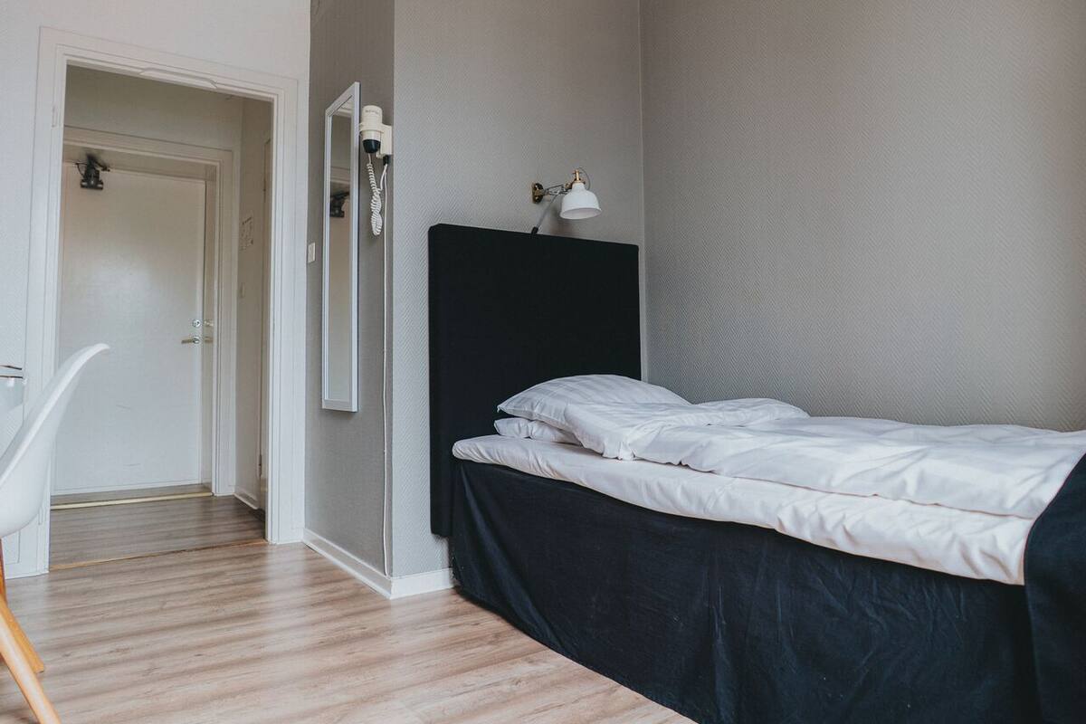 A bedroom with a bed, a chair, a wardrobe, and a door.