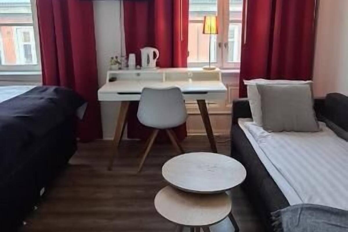A room with a bed, a desk, a chair, and a TV.