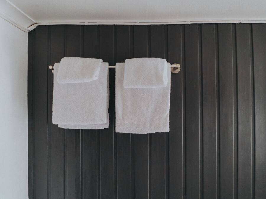 Two white towels hanging on a dark wooden door.