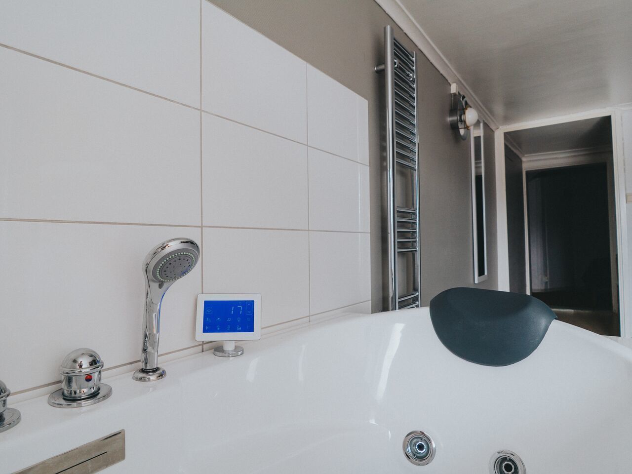 A modern bathroom with a white bathtub, a digital shower control panel, and a chrome faucet.