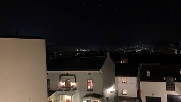 Vista nocturna de una zona residencial con casas, un camino de entrada pavimentado y un coche estacionado en primer plano.