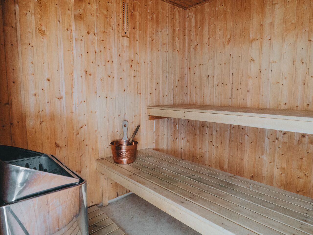 Un sauna en bois, doté de bancs et d’un seau en cuivre.