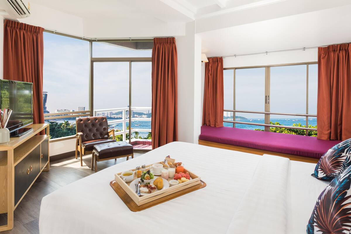 A hotel room with a large bed, a TV, a wooden desk, and a breakfast tray.