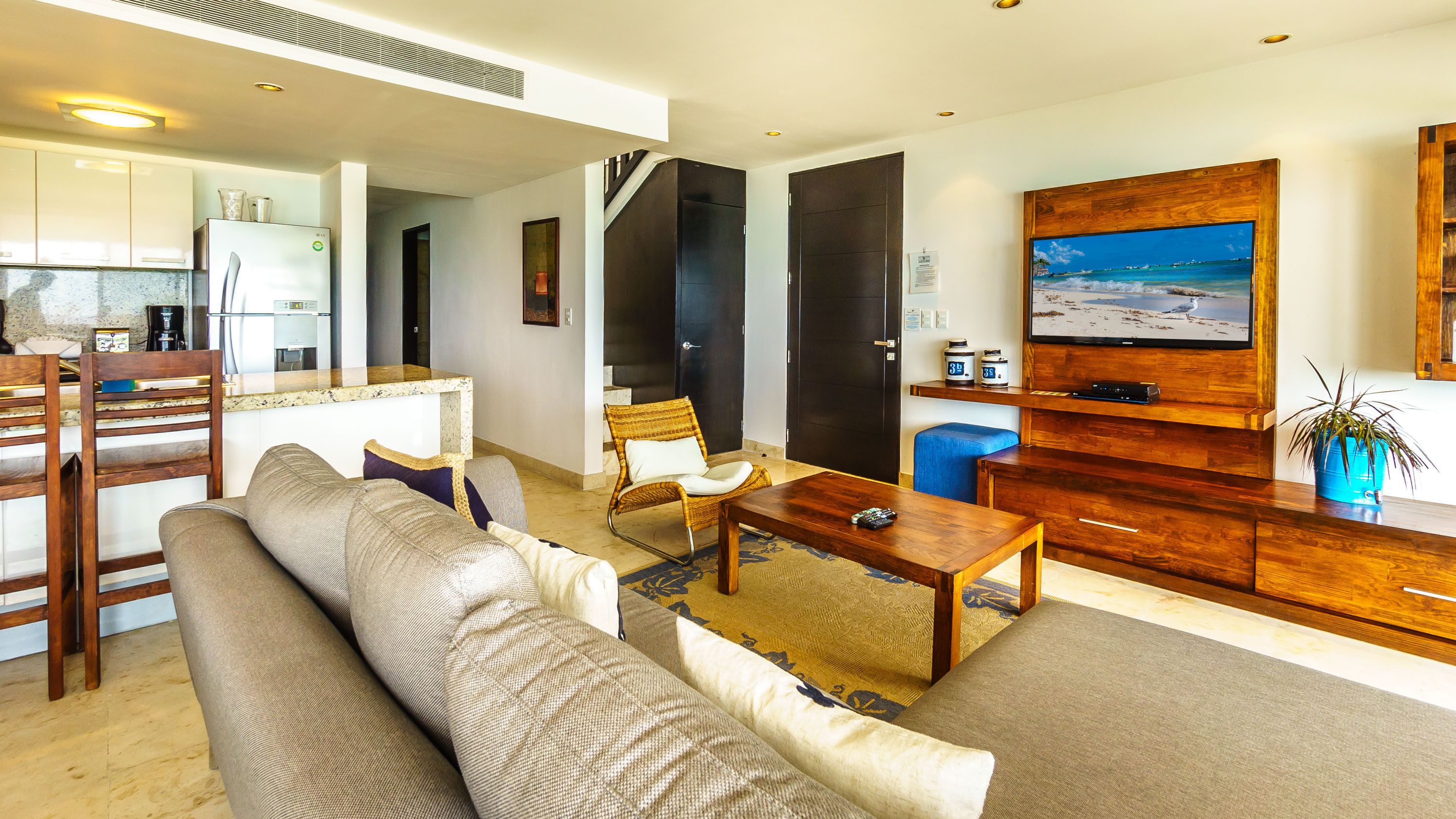 A modern living room with a sofa, coffee table, and a TV mounted on a wooden wall.
