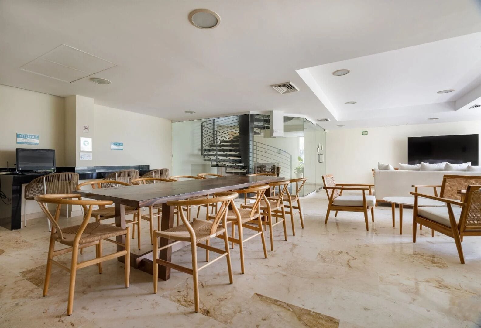 A spacious room with a long wooden table and chairs, a sofa, and a TV.