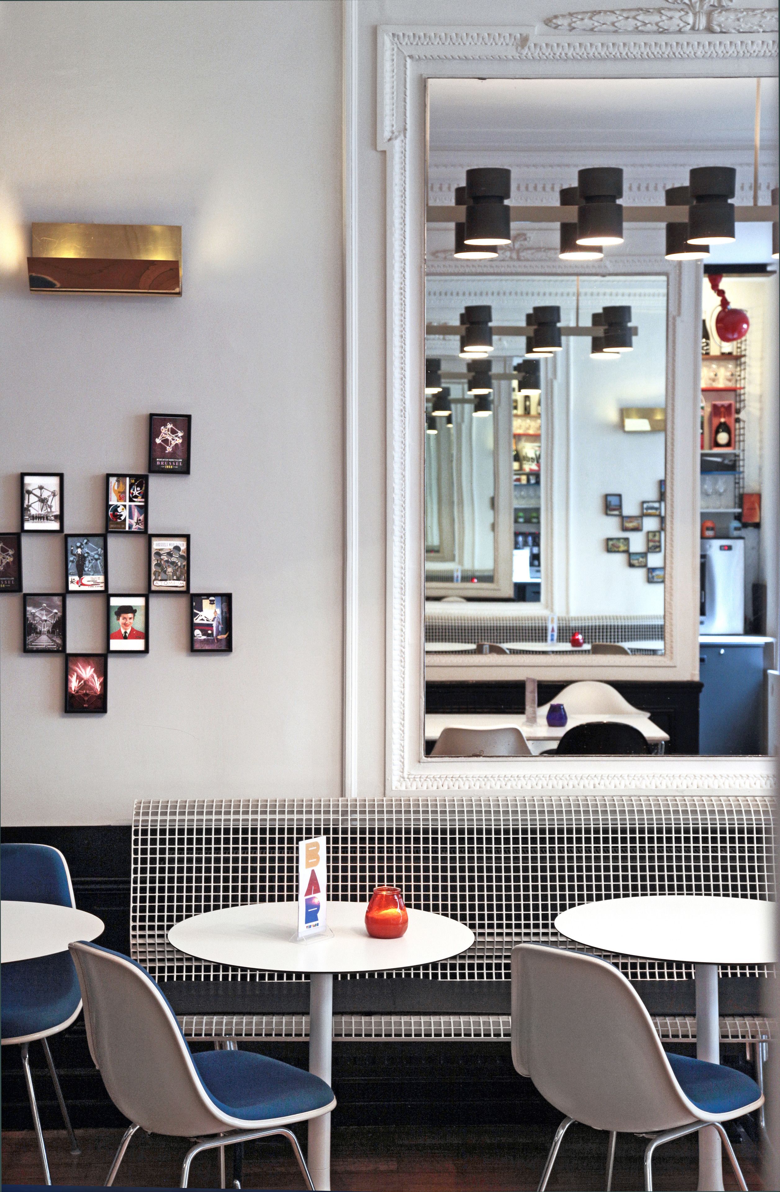 A restaurant with a mirrored wall, framed pictures, and a seating area with tables and chairs.