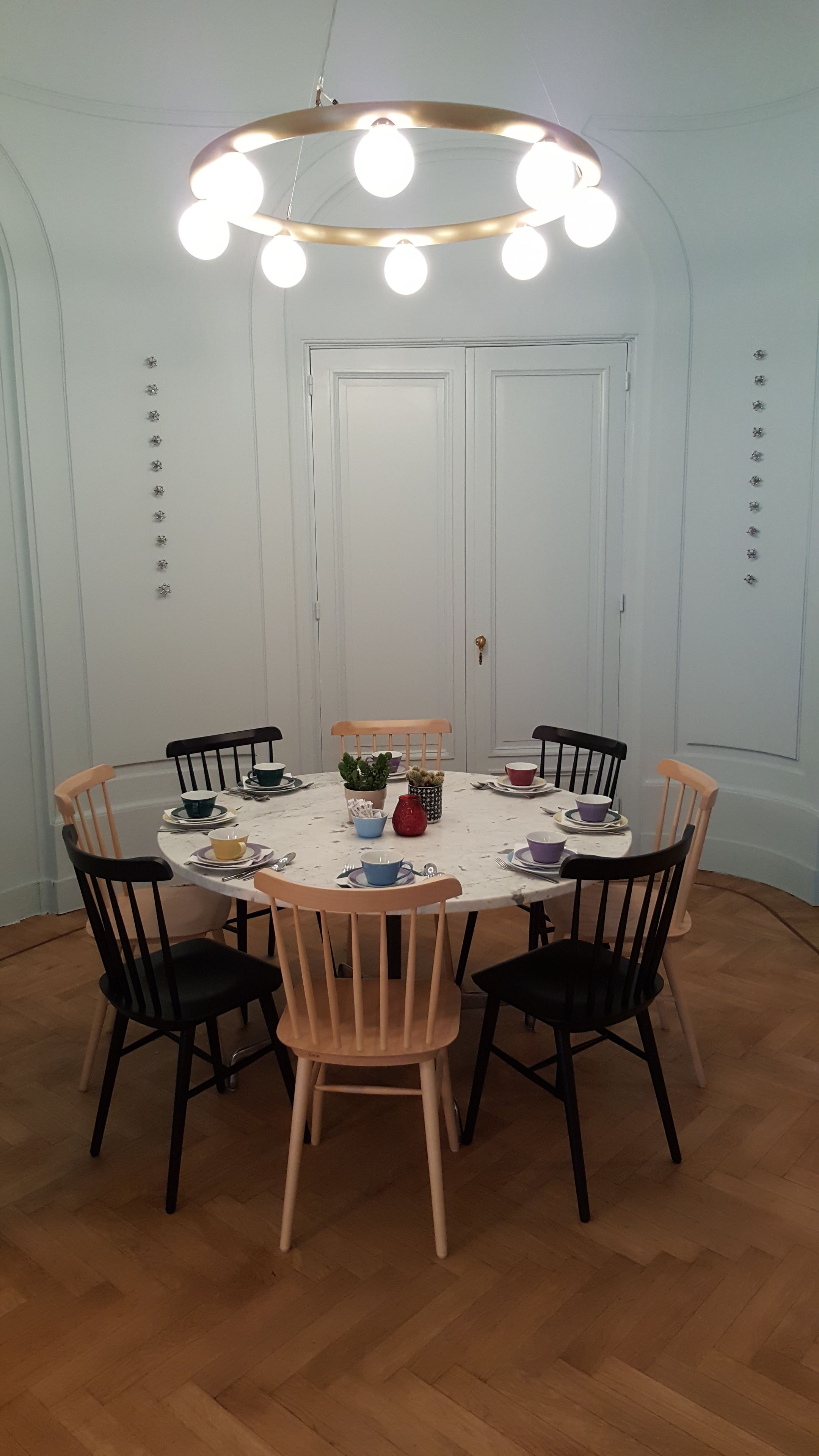Un comedor con una mesa redonda, seis sillas y una lámpara en el techo.