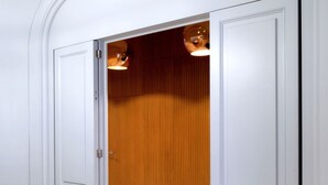 A hallway with white doors and a wooden wall.