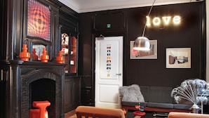 A cozy living room with a fireplace, wooden furniture, and a wall-mounted light fixture displaying the word "love".