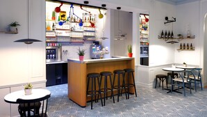 A modern bar area with a wooden counter, bar stools, and a seating area with tables and chairs.