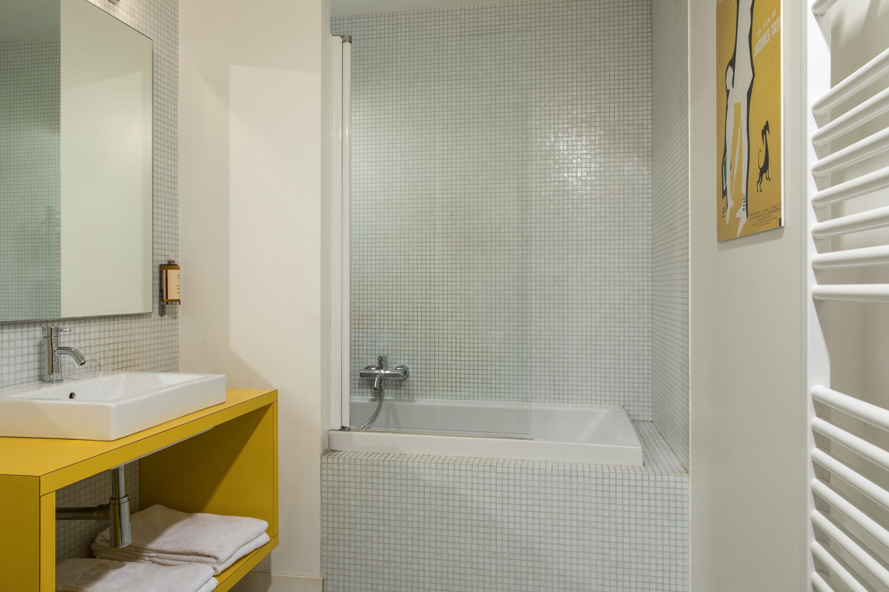 A bathroom with a white sink, mirror, and tiled walls.