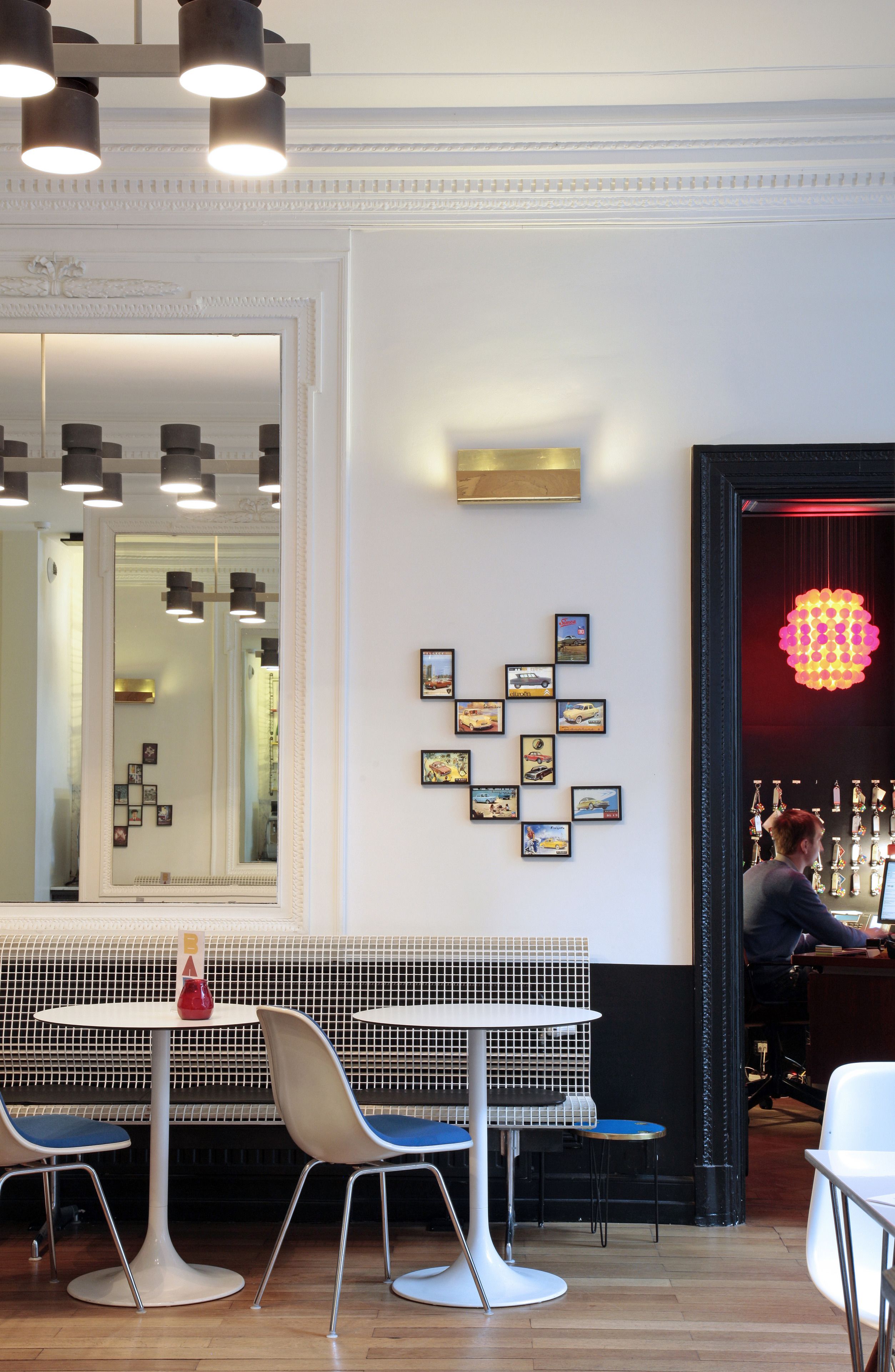 A modern interior with a white bench, a round table, and a bar area with a bartender.