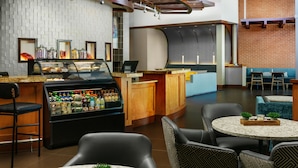 A modern bar area with a counter, seating, and a display case with snacks. - Hyatt Place Ft. Lauderdale Airport & Cruise Port (Dania Beach)