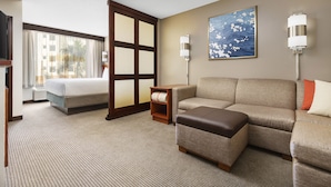 A hotel room with a bed, sofa, ottoman, and a large window with curtains. - Hyatt Place Ft. Lauderdale Airport & Cruise Port (Dania Beach)