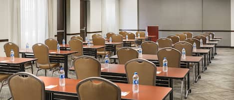 A conference room with rows of tables and chairs, equipped with water bottles.