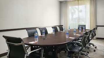 A conference room with a long table, black chairs, and water bottles on the table.