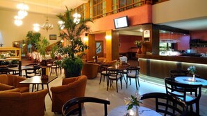 Eine Hotelhalle mit mehreren Sitzbereichen, einer Bar und einem Fernseher.