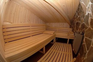A sauna with wooden benches and a stone wall. - Hotel Grand Matej (Banska Stiavnica)