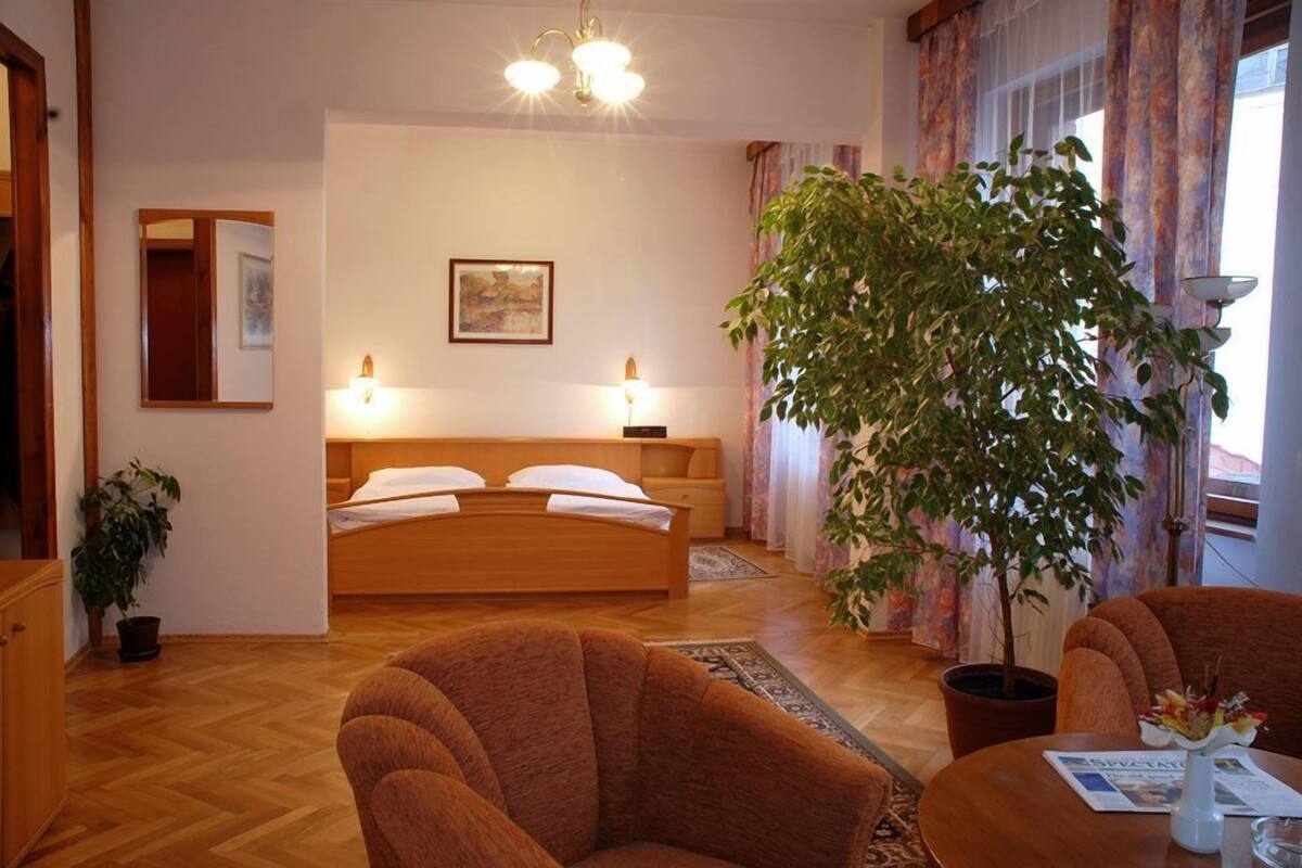 Une chambre à coucher avec un lit, des lampes de chevet, une grande plante en pot et un plancher en bois.