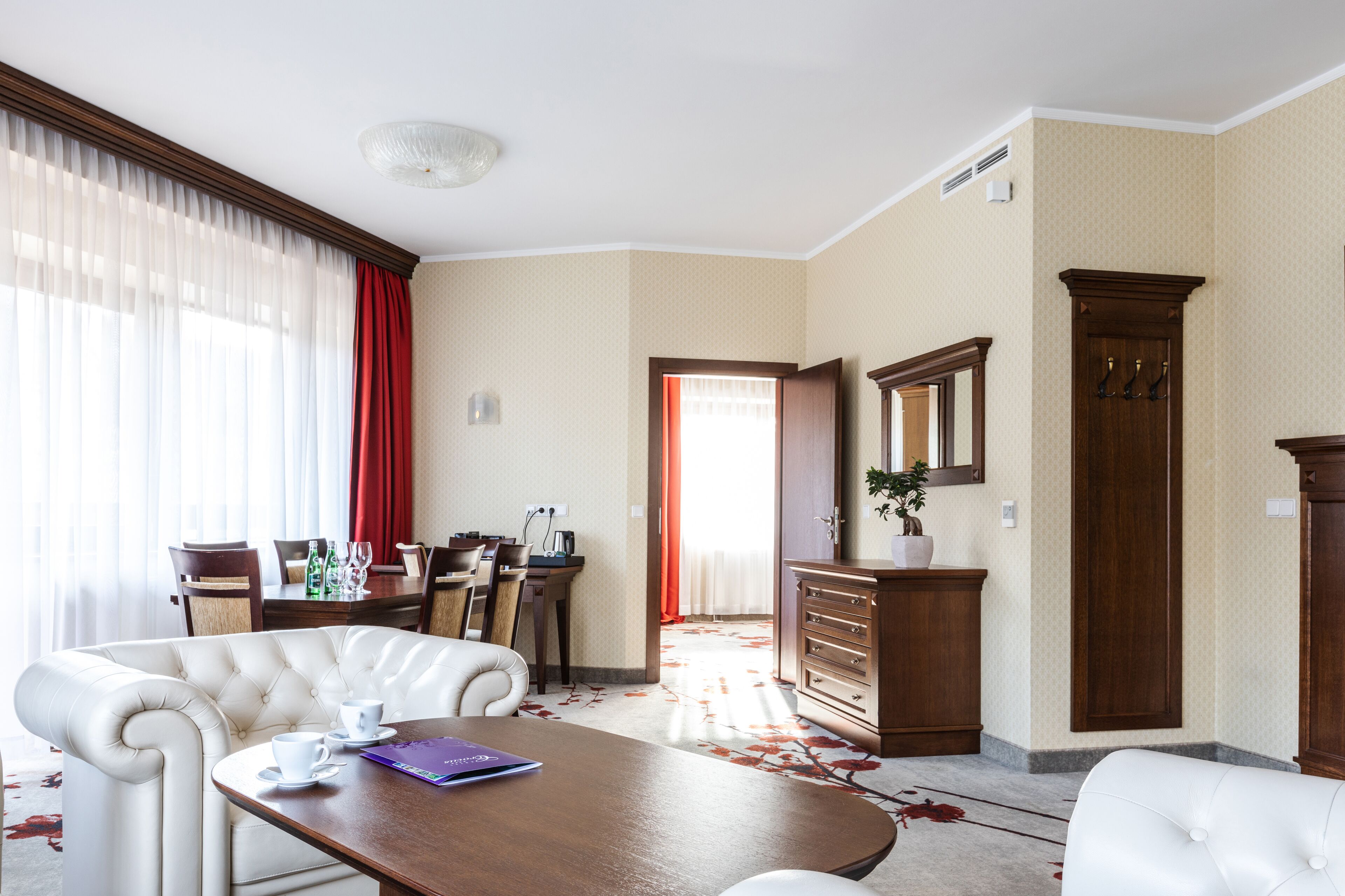 Habitación de hotel con comedor, un espejo grande y un mueble de madera.