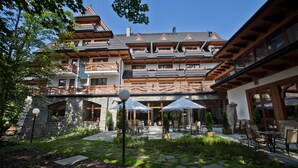 A traditional chalet with multiple balconies, stone walls, and outdoor seating areas. - Hotel Crocus (Zakopane)