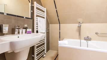 Un baño moderno con un lavamanos blanco, una bañera y un perchero para toallas.