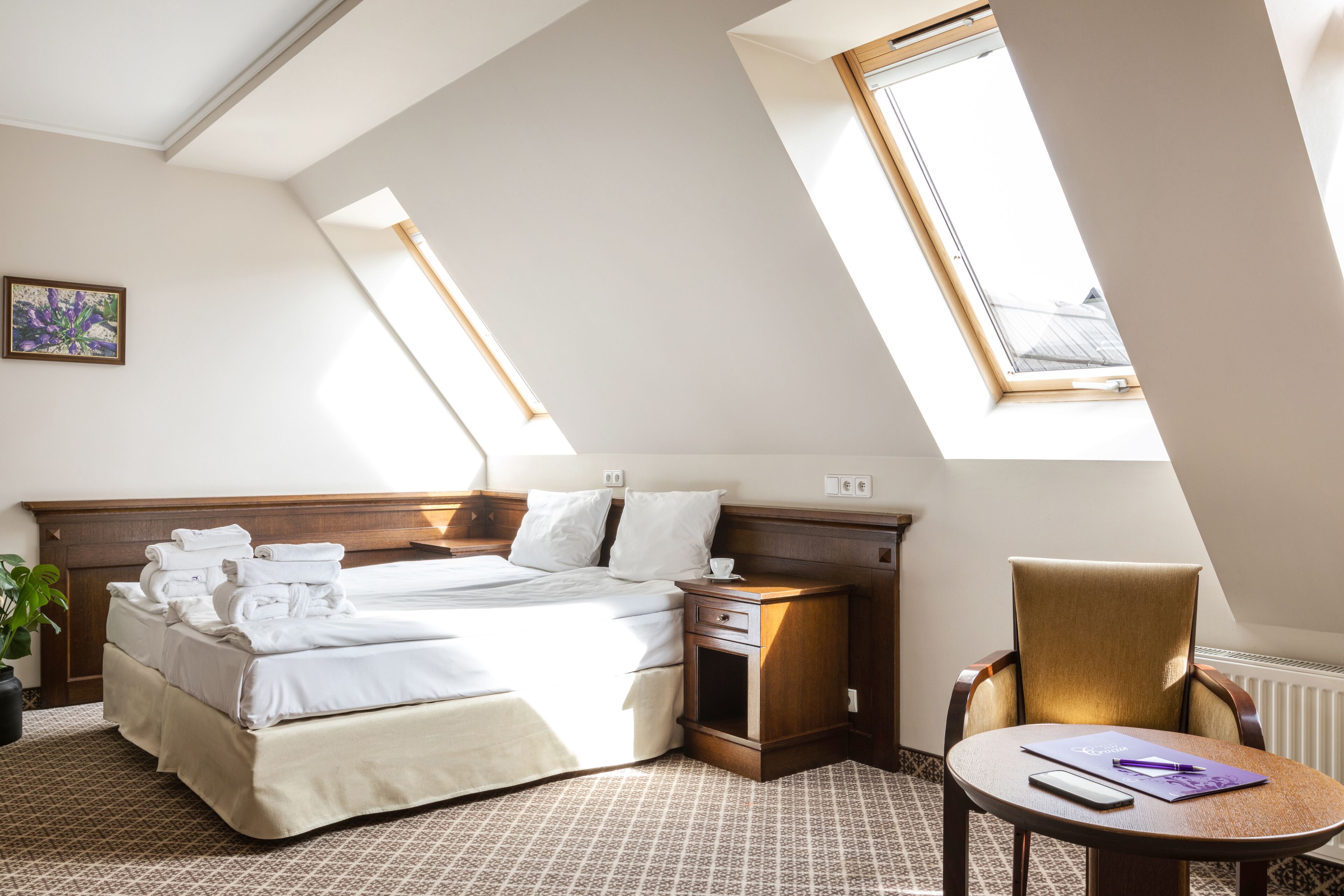 Habitación de hotel con una cama grande, una mesita de noche, una silla y una pequeña mesa.