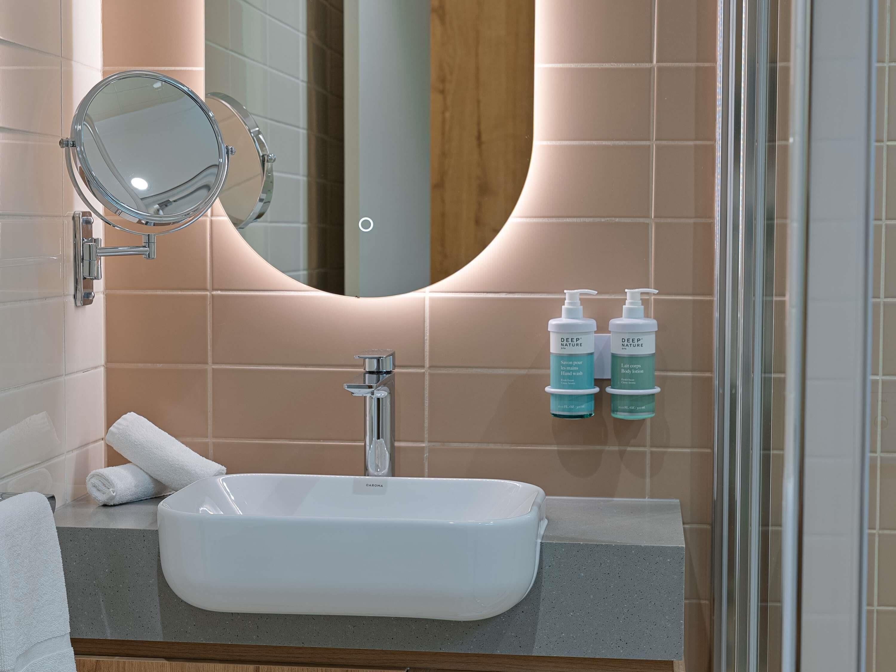 A bathroom with a white sink, a mirror, and two bottles of hand wash and body wash.