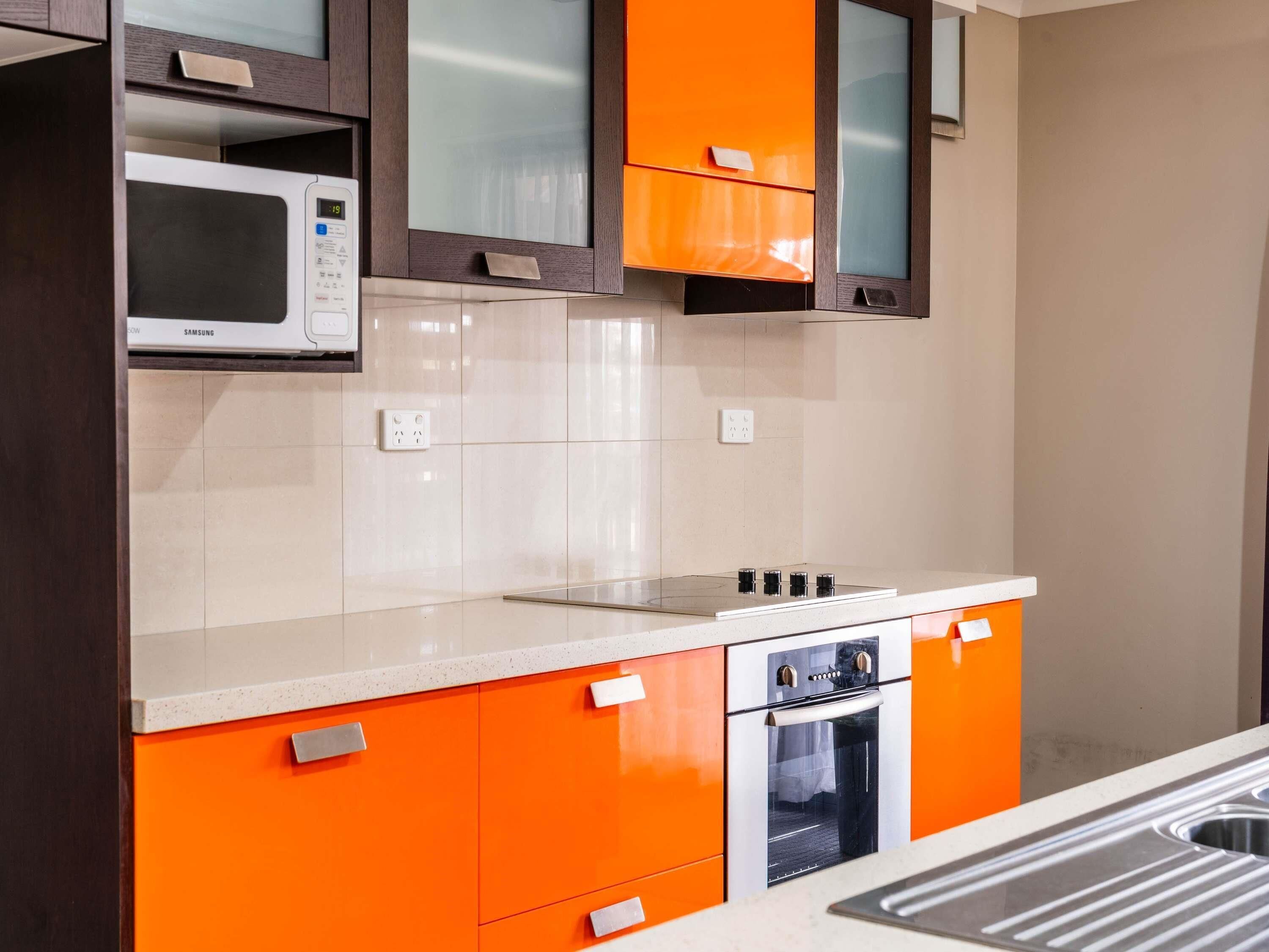 A kitchen with a microwave, oven, and stainless steel sink.