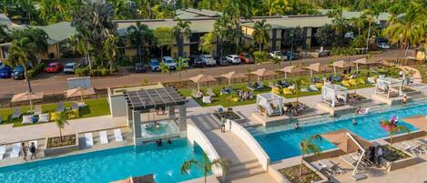 A resort with a large pool, sun loungers, and a covered area.