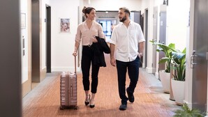 A hotel hallway with a wooden floor, doors on both sides, and potted plants. - Novotel Darwin Airport (Eaton)