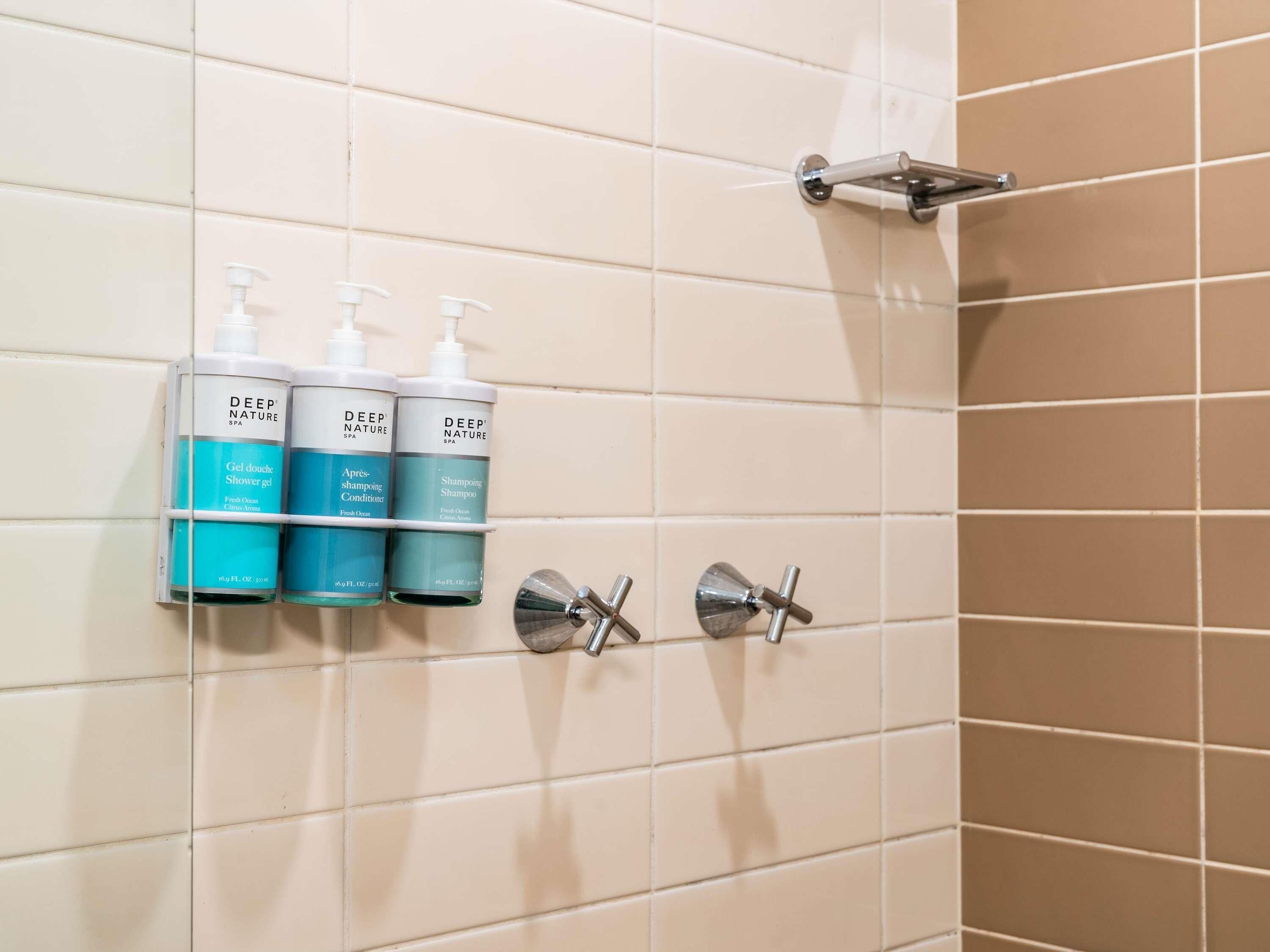 A bathroom with three bottles of Deep Nature Spa products on a wall-mounted shelf.