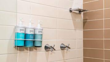 A bathroom with three bottles of Deep Nature Spa products on a wall-mounted shelf.