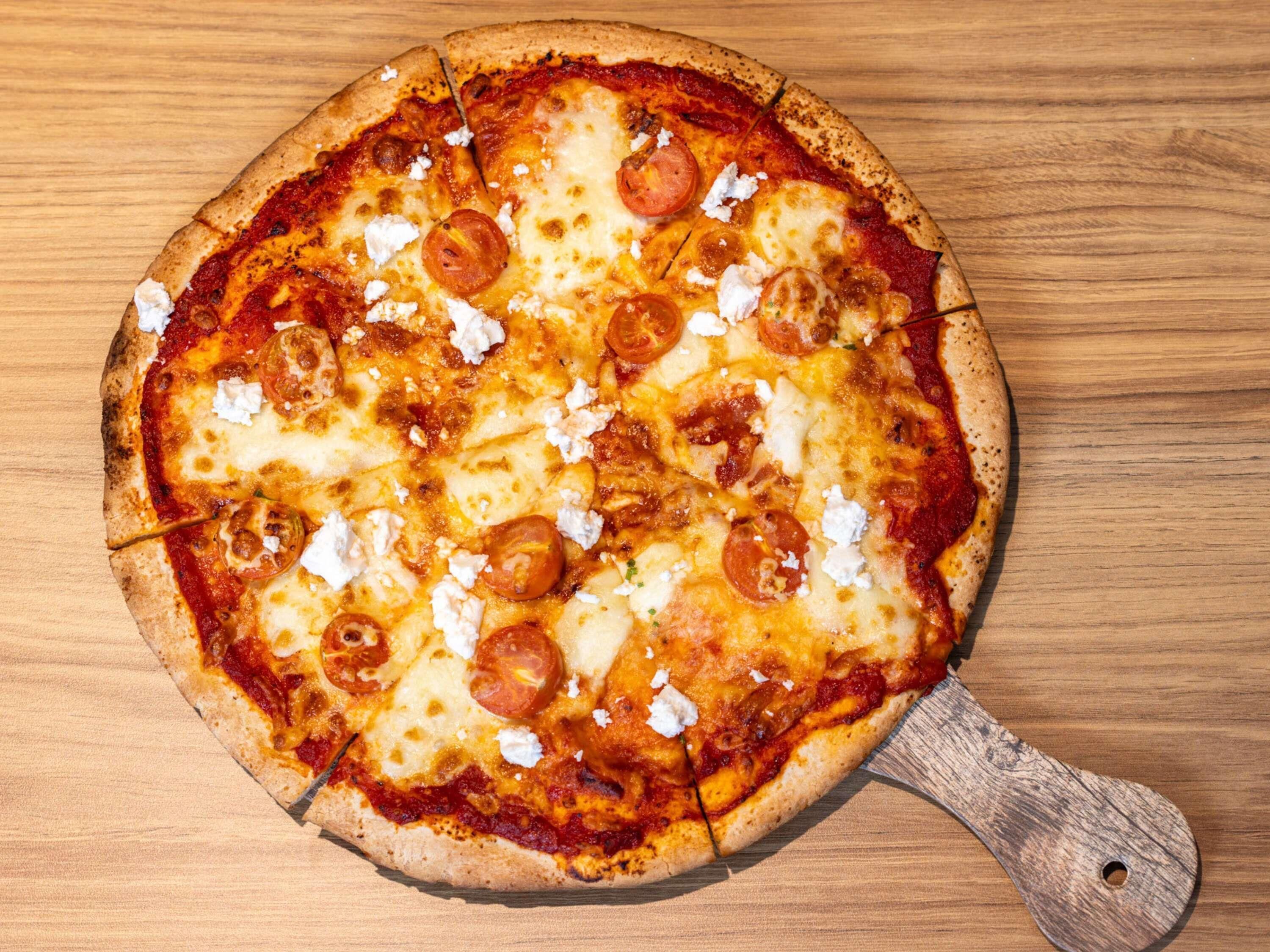 Une pizza servie sur une planche en bois.