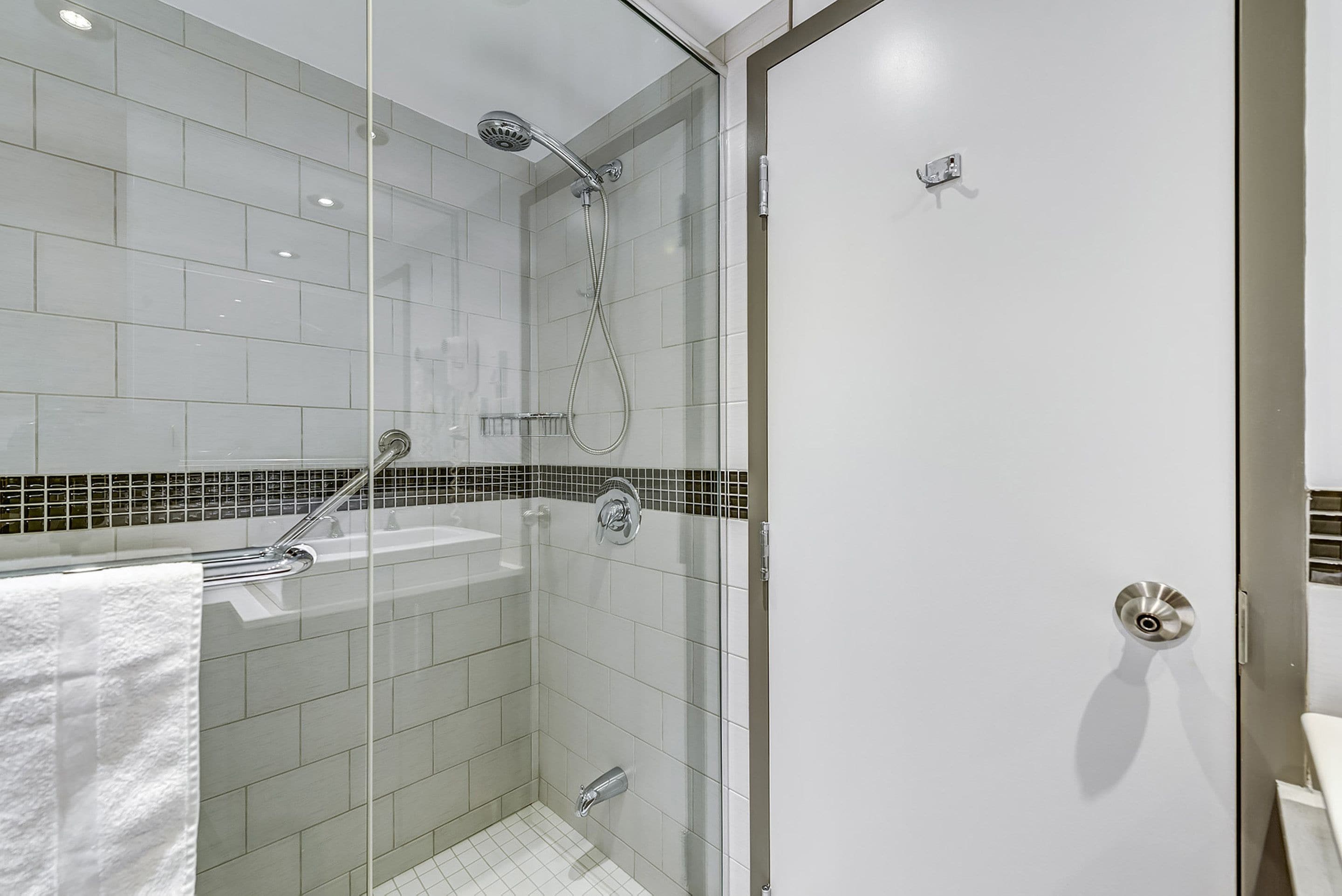 Ein modernes Badezimmer mit einer gläsernen Duschkabine, einer weißen Badewanne und einem Fliesenboden.