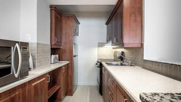 Una cocina con armarios de madera, un refrigerador de acero inoxidable, un microondas, un tostador y un lavavajillas.