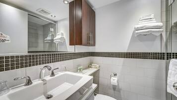 Un baño moderno con un espejo grande, un lavabo blanco y una cabina de ducha de vidrio.