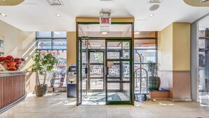 A hotel entrance with a revolving door, a reception desk, and a potted plant. - Hotel Terrasse Royale (Montreal)