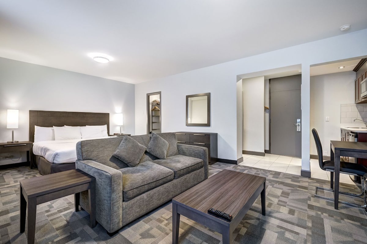 A hotel room with a bed, a sofa, a coffee table, a desk, and a chair.