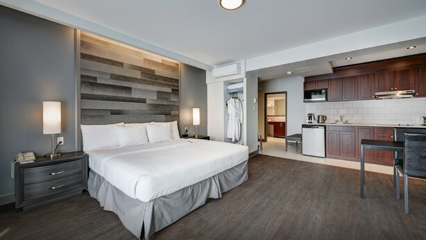 A modern hotel room with a large bed, bedside tables, a desk, and a kitchenette. - Hotel Terrasse Royale (Montreal)