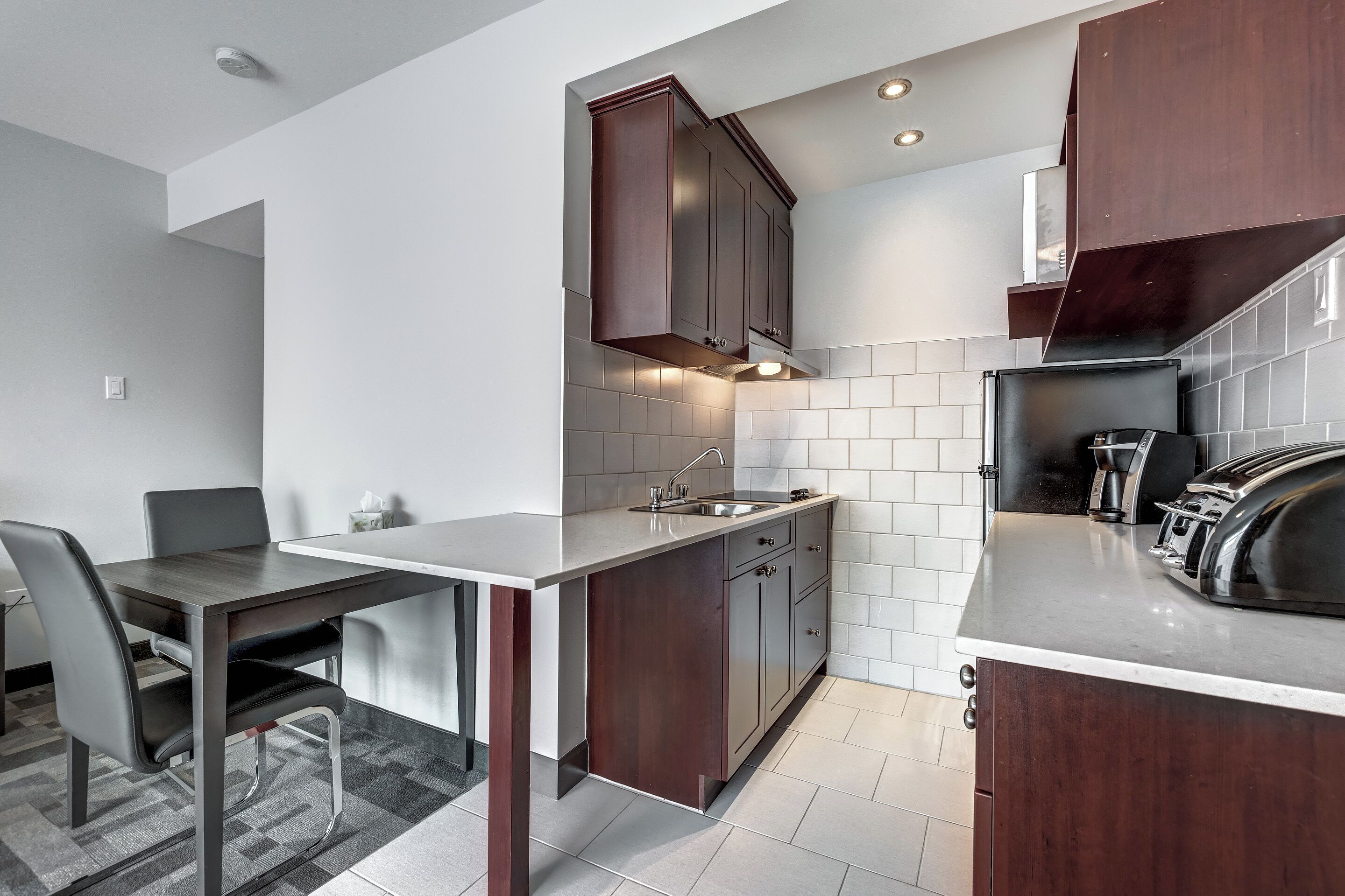 A modern kitchen with dark wood cabinets, a stainless steel sink, and a built-in oven.