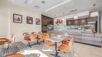 Un ristorante moderno con diverse opzioni di posti a sedere, tra cui tavoli e sedie, e un bancone con esposizione di prodotti alimentari.