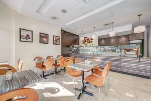 A modern restaurant with a variety of seating options, including tables and chairs, and a counter area with a display of food items.
