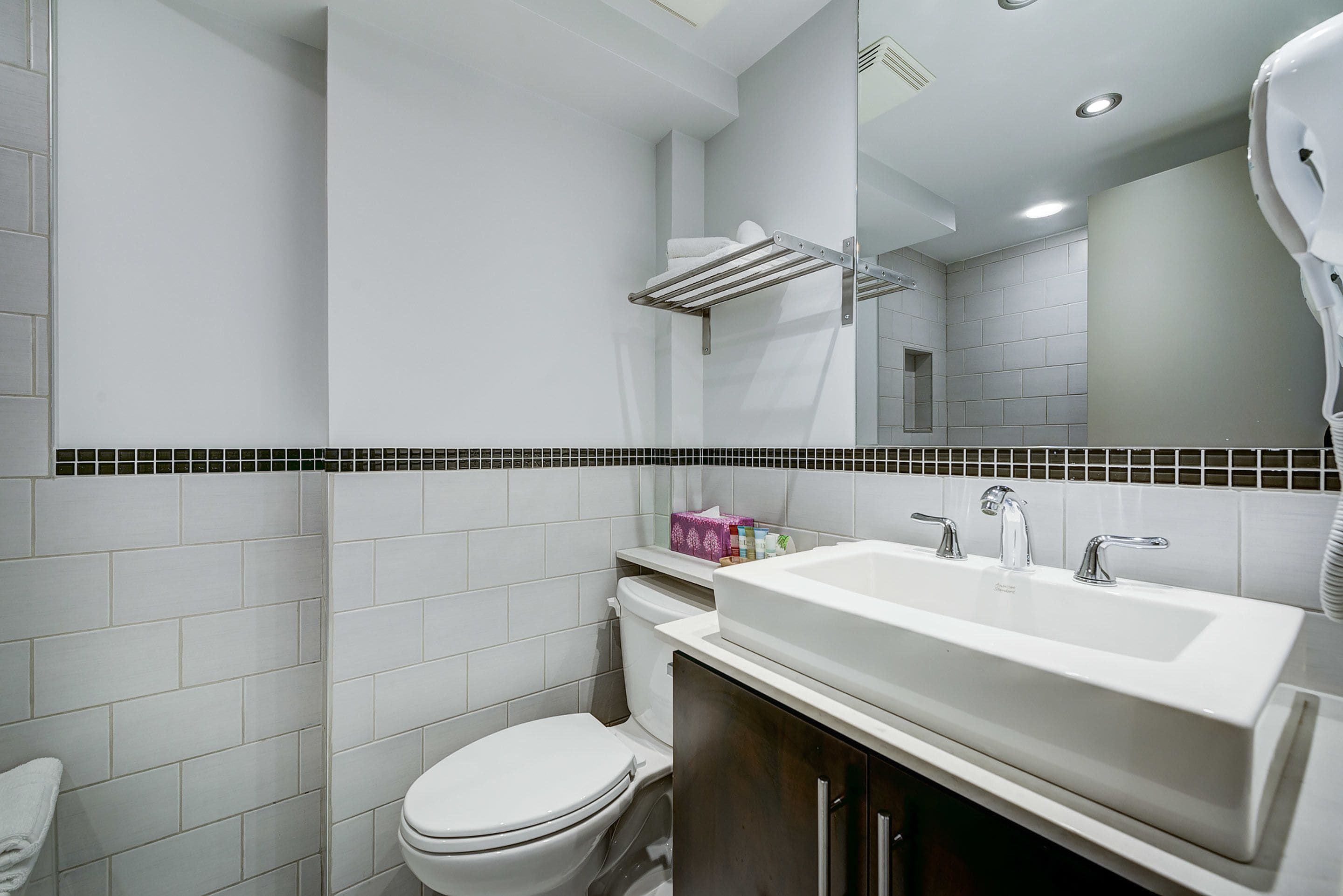 Uma casa de banho moderna com uma sanita branca, uma loiça e um chuveiro.