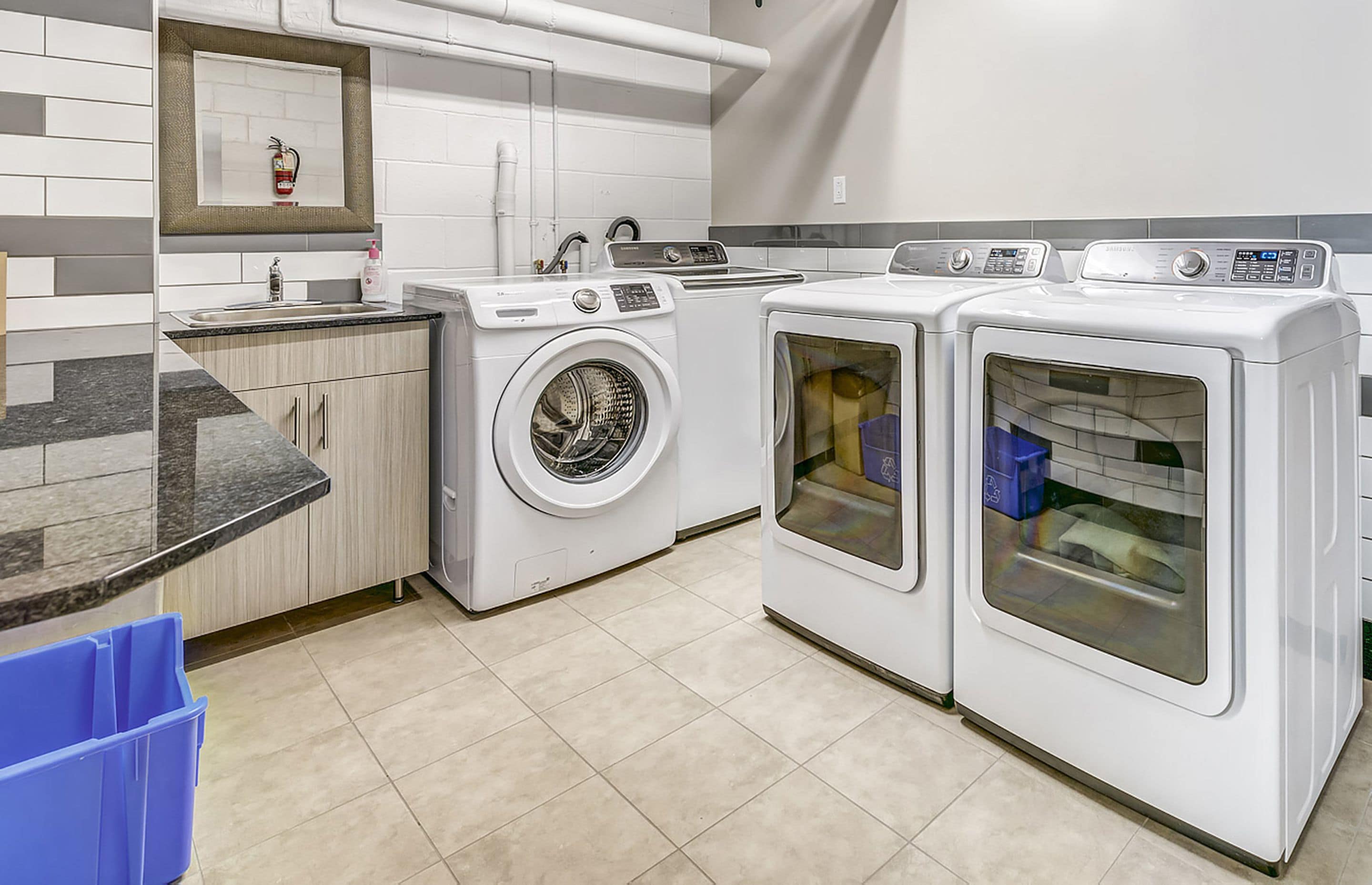 A modern laundry room with a washing machine, dryer, and countertop with a sink.